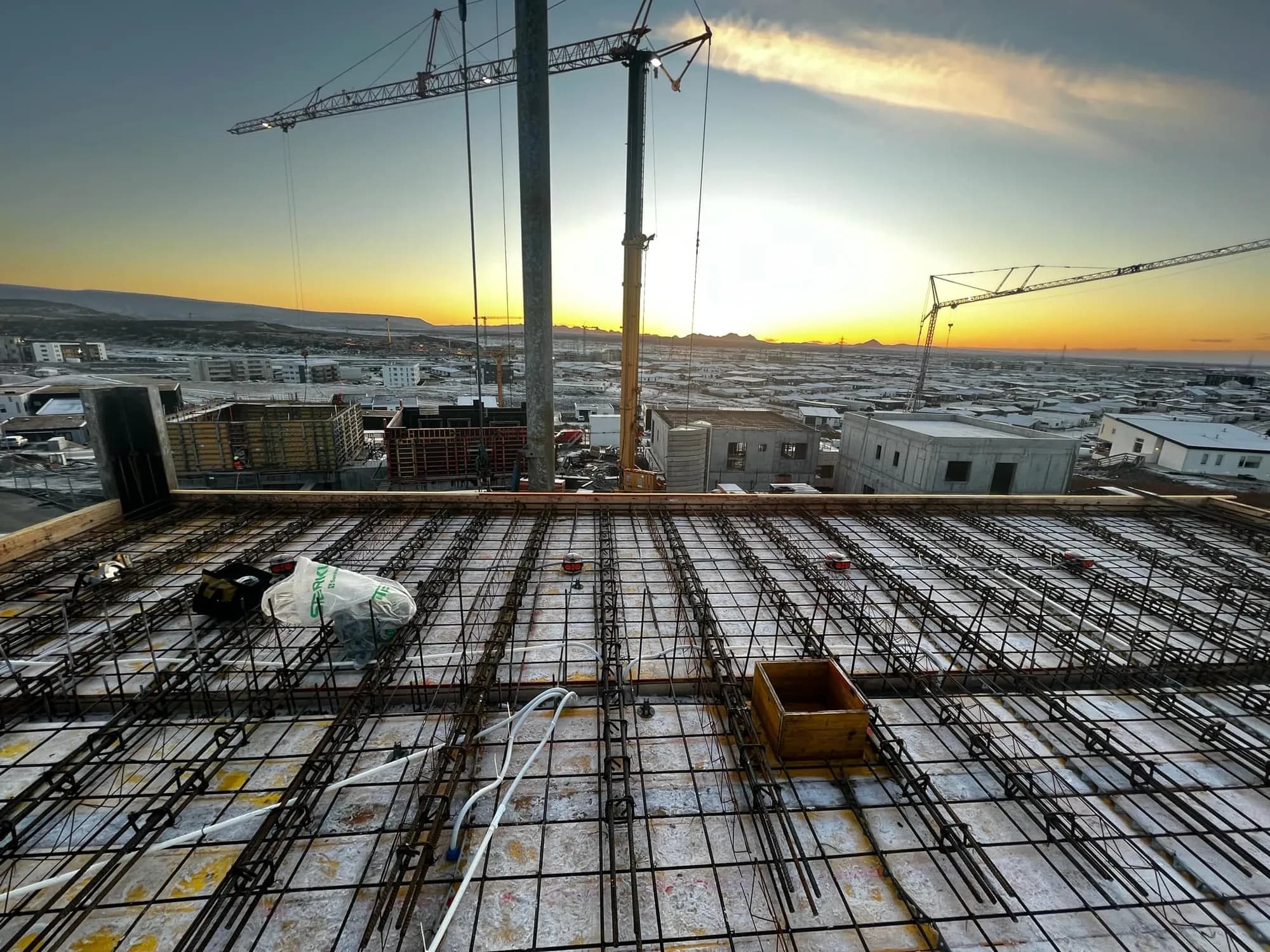 Floor slab with conduits and a construction crane at sunset