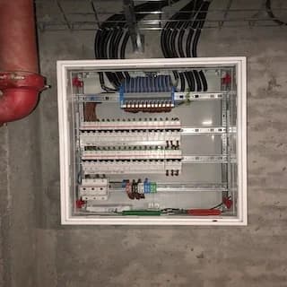 Distribution board on a concrete wall, fed from a cable tray